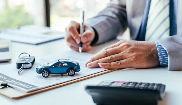 A homeowner reviews a renewal policy beside a calculator, vehicle keys, and house documents.